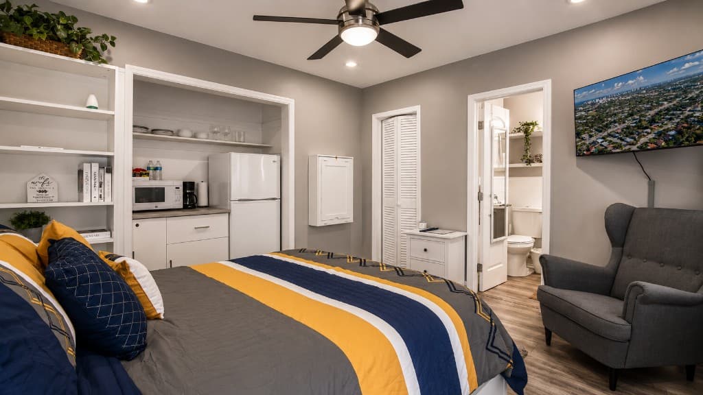 One-bedroom studio overview with bed, kitchenette, lounge chair, and wall-mounted TV